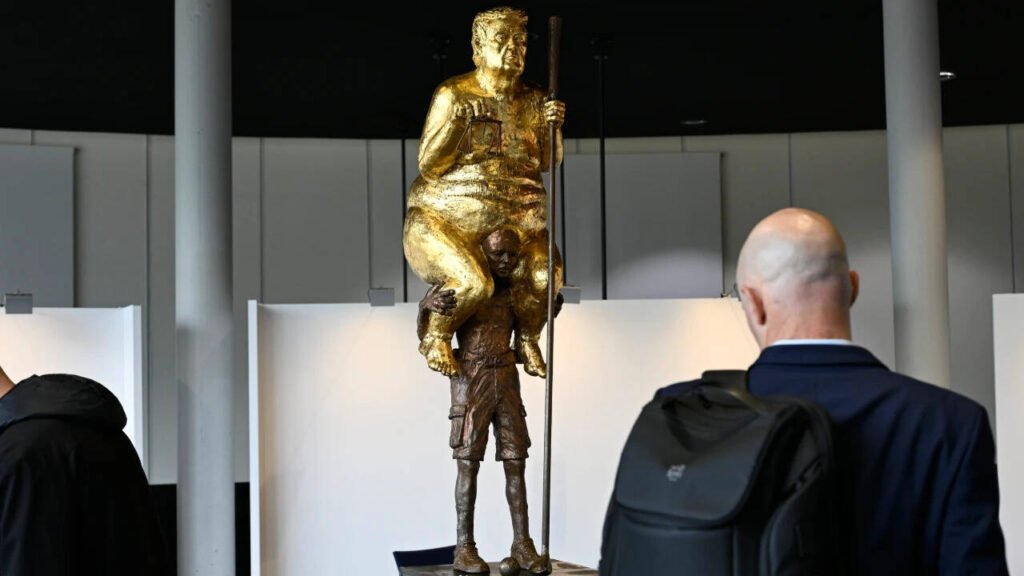 ‘The Orange Plague’: Why a golden, naked Trump is sitting on another man